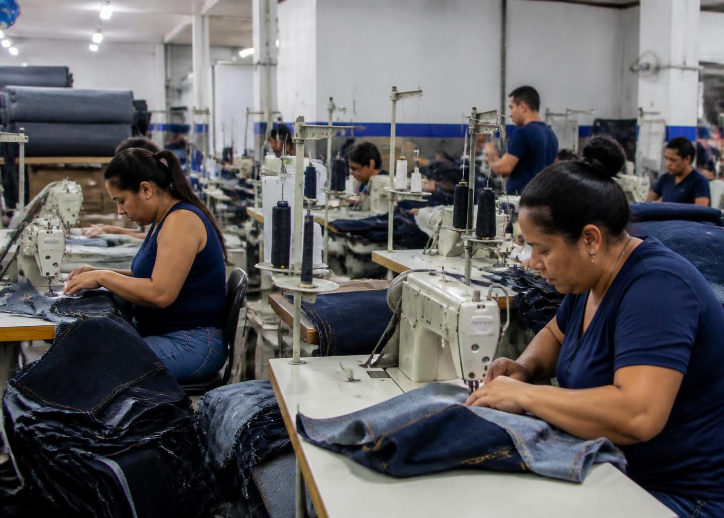 Interior da fábrica de jeans com máquinas de costura em operação